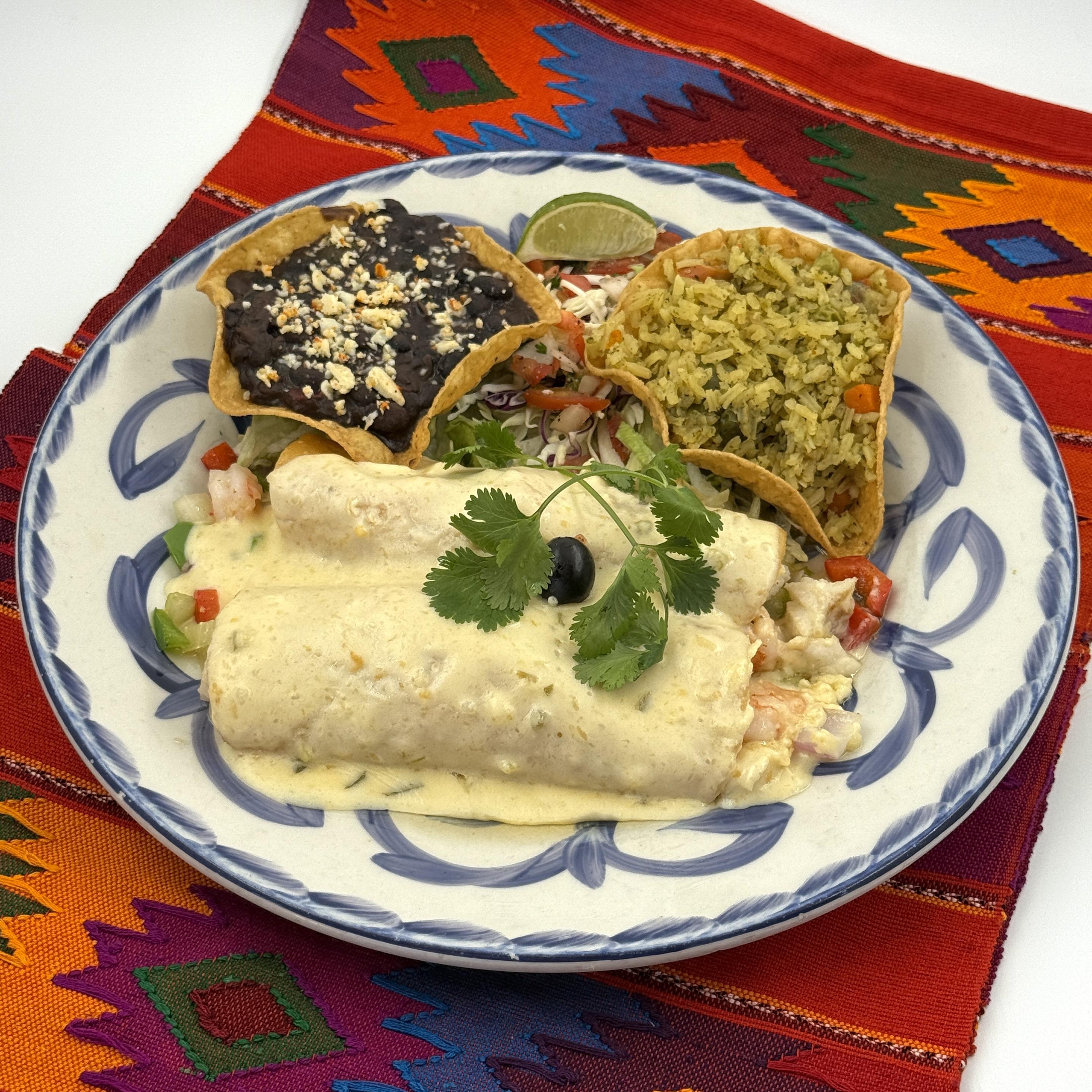 Two enchiladas with shrimp, pescado blanco and vegetables. Topped with creamy jalapeño sauce and served with rice and black beans.