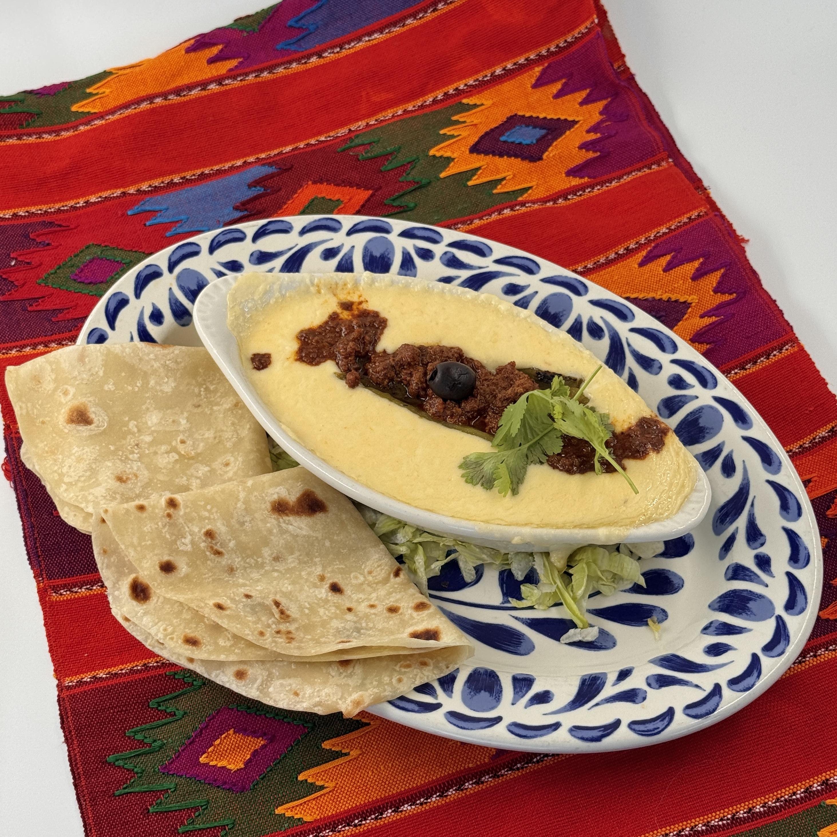 Queso Fundido, Rich gooey goodness of melted Jack cheese, topped with a layer of beef chorizo that's bursting with flavor. Served alongside our homemade flour tortillas.