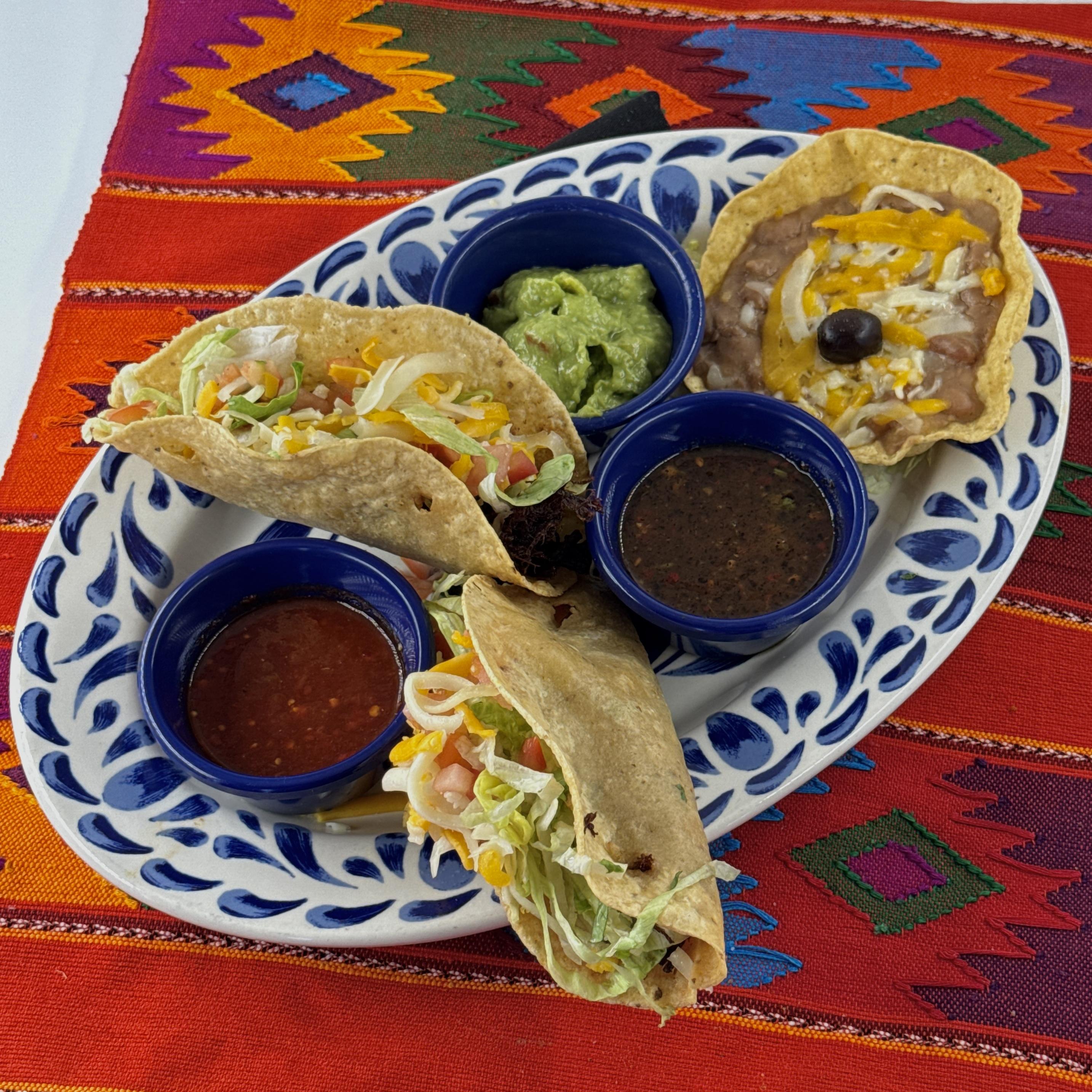 Tacos Victorioso, Two Mexican style tacos with tender shredded beef in a traditional fried taco shell. With a concha of Pico beans, guacamole and three salsas