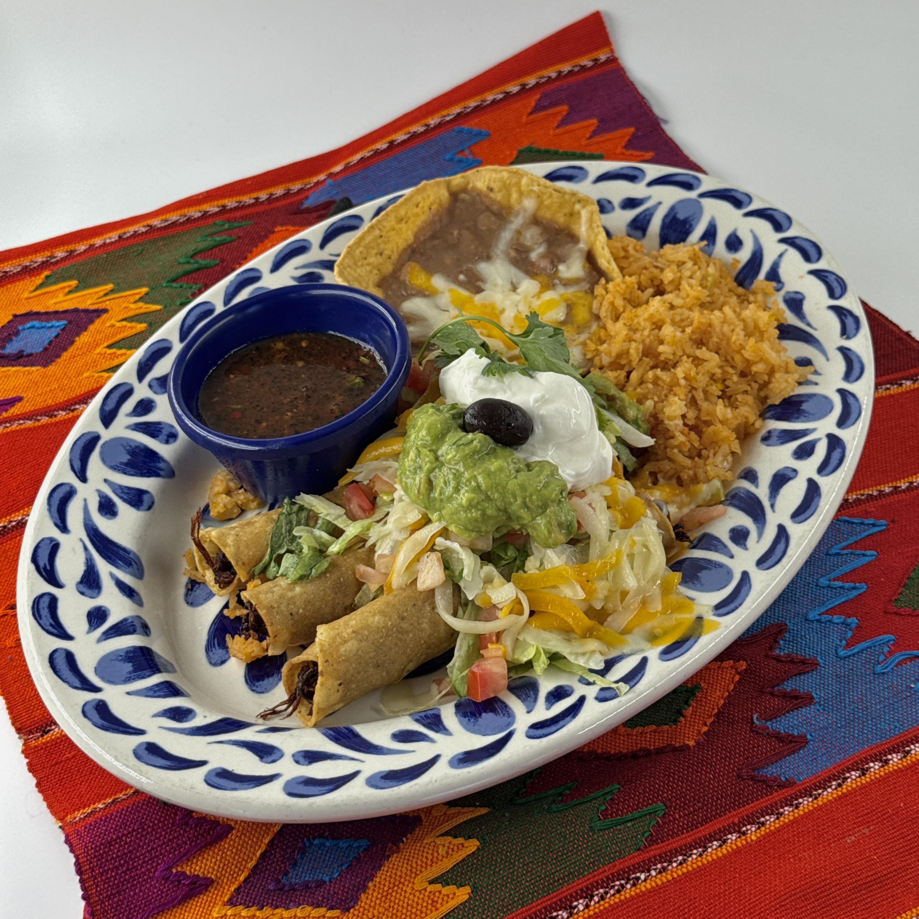 Taquitos Rancheros,Three rolled crisp corn tortillas with shredded seasoned beef, topped with shredded lettuce, chopped tomatoes, and cheese. Served with guacamole, sour cream and rice, beans and salsa quemada on the side.
