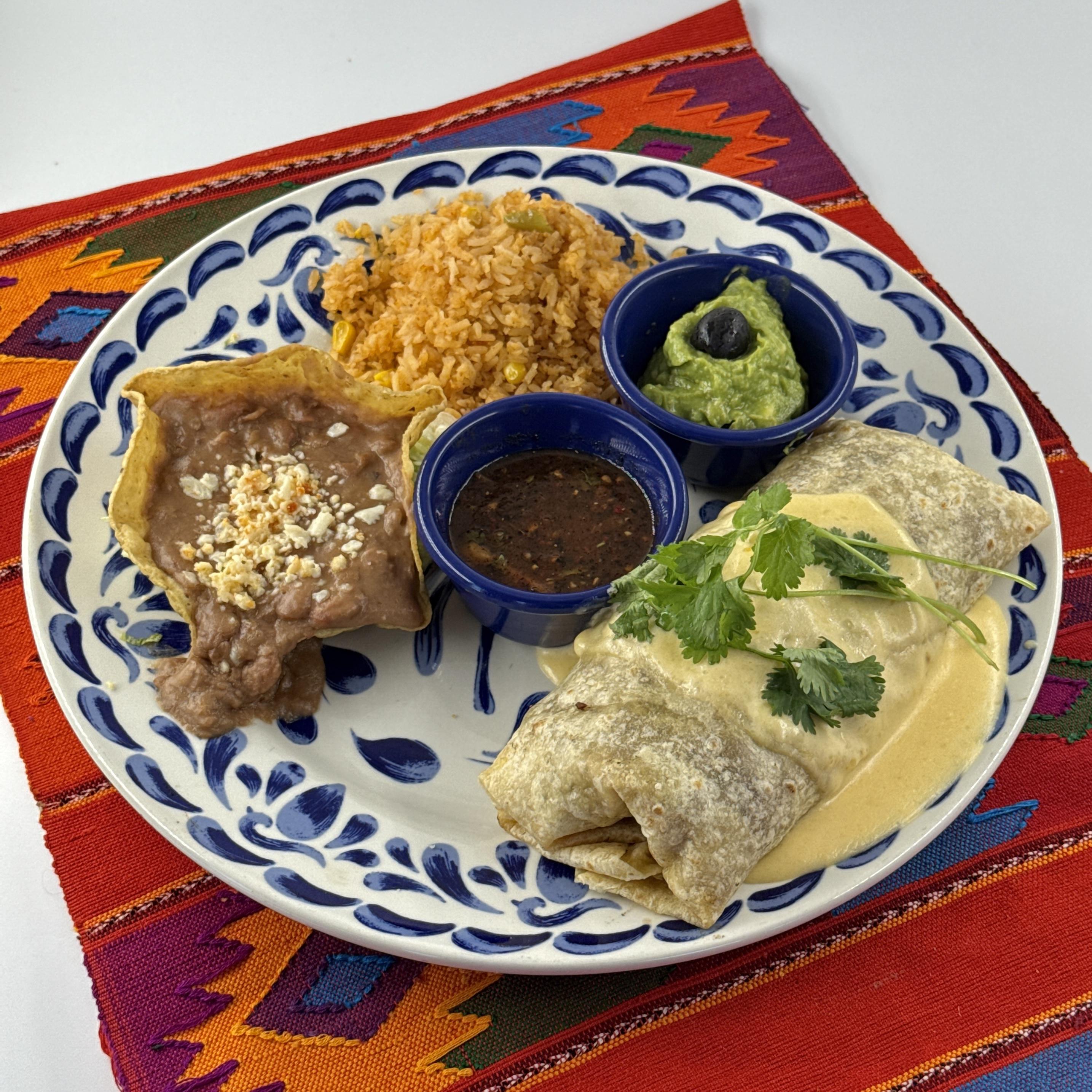 Carne Asada Burrito, A large burrito filled with marinated carne asada, and pico de gallo. Topped with cheese sauce and guacamole. With refried beans and rice.