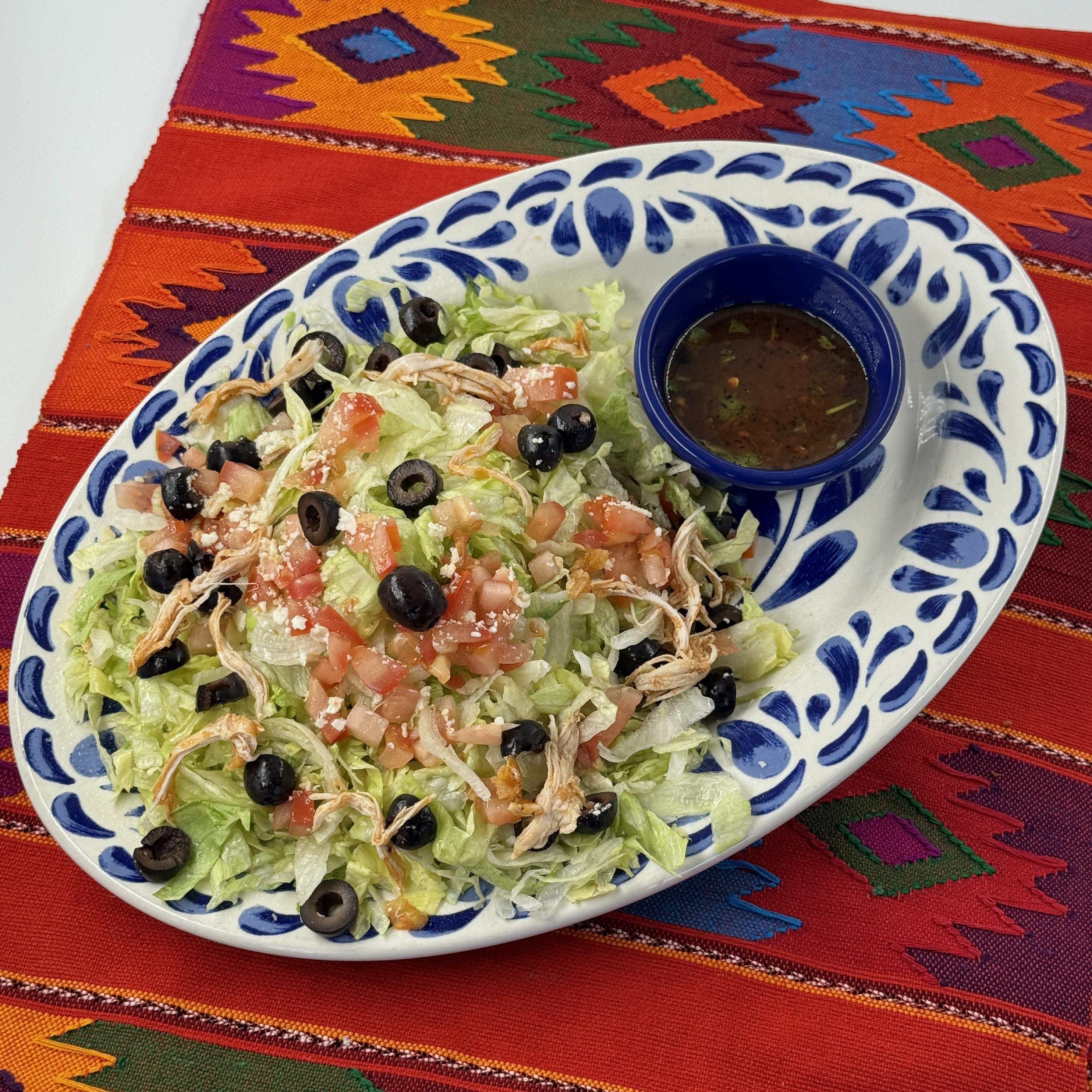 CHICKEN & BLACK BEAN TOSTADA , A crisp chipotle tortilla topped with shredded chicken, black beans, lettuce, tomato, olives and Mexican chile cheese with salsa quemada