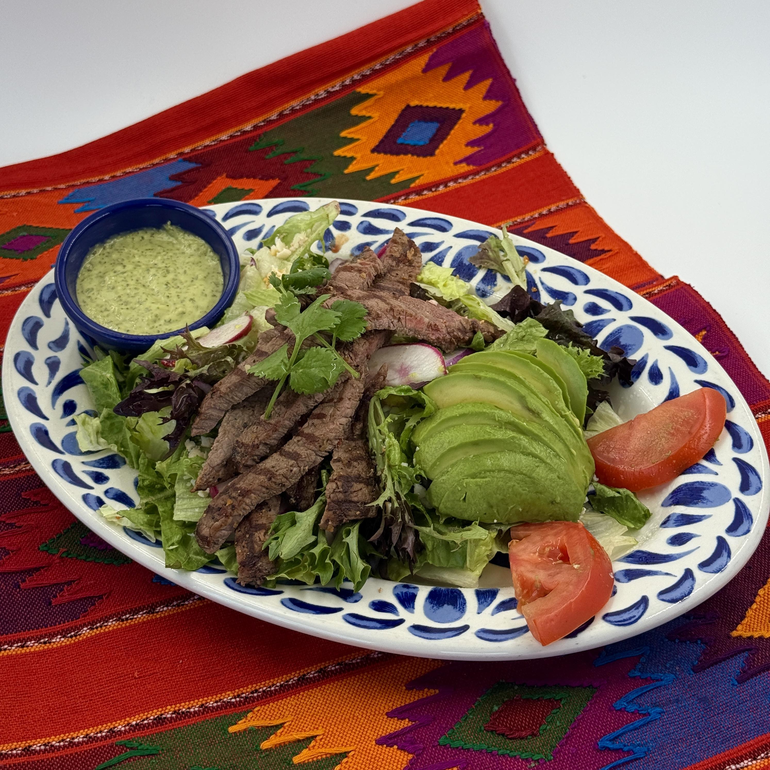 Ensalada De Carne Asada, Enjoy flavorful carne asada served with avocados, tomatoes, and sliced radishes over a bed of mixed greens. Tossed in our tangy cilantro lime dressing and garnished with crumbled cotija cheese.