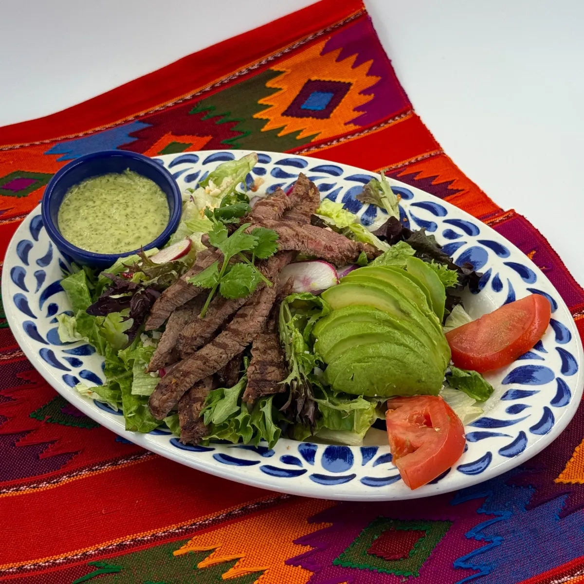 Ensalada de carne asada with sliced steak, avocado, tomatoes and dressing