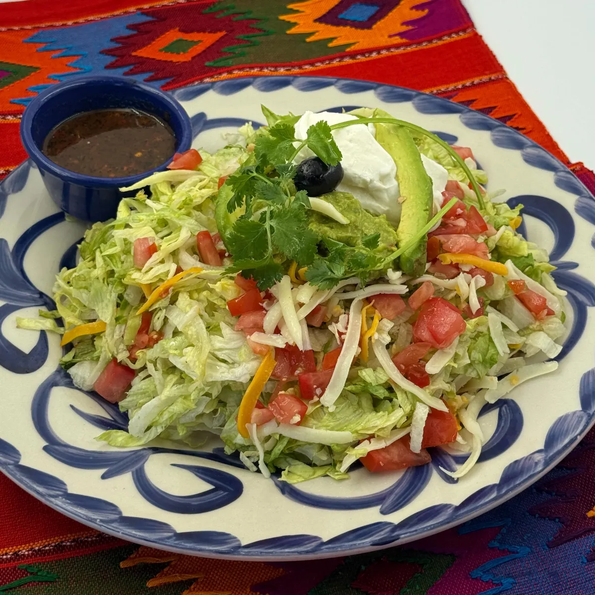Tostada del Mundo piled with lettuce, tomatoes, cheese and sour cream