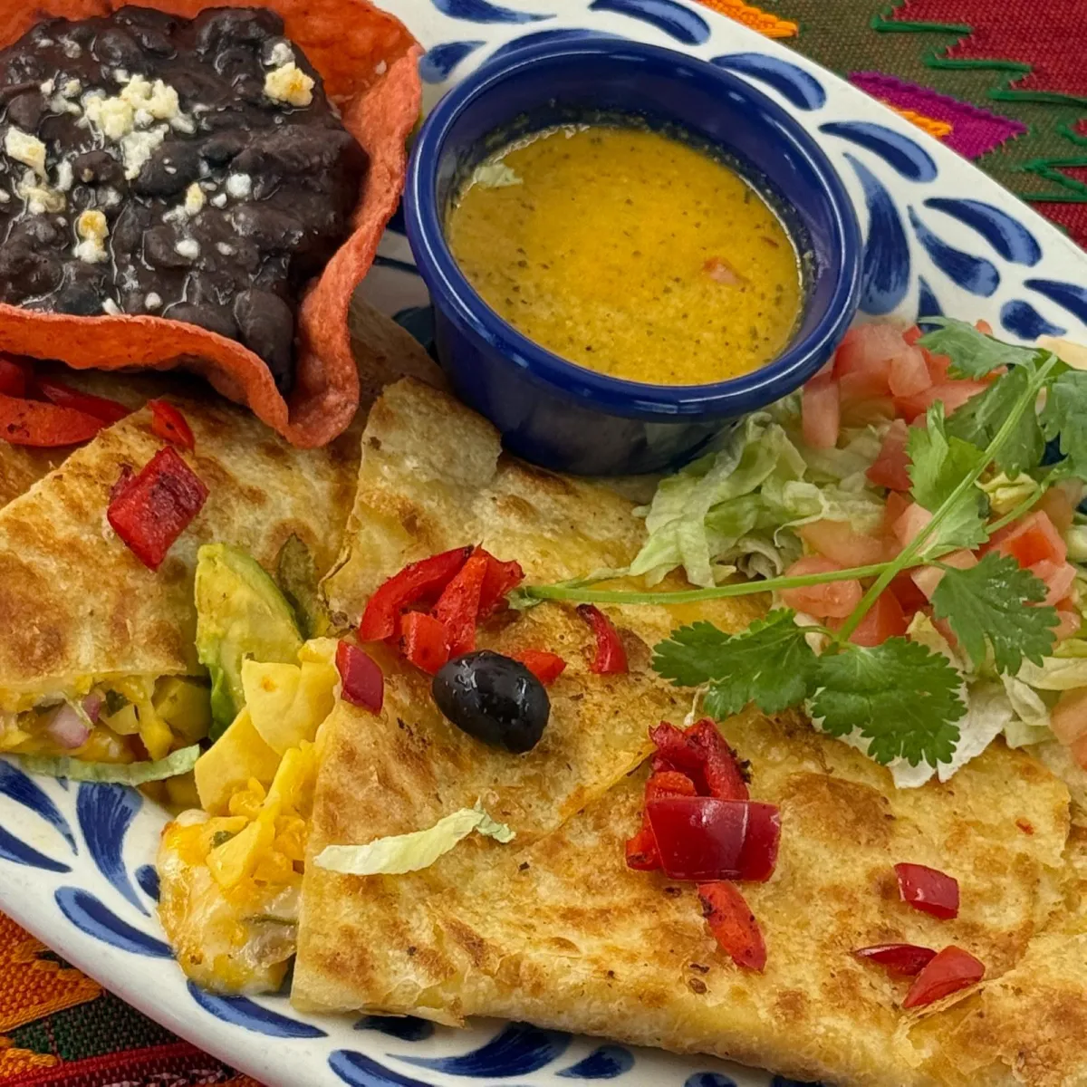 Casa de Pico avocado mango and red pepper quesadilla, topped with lettuce and tomatoes, served with black beans