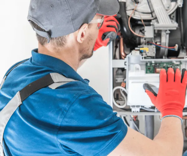 Technician performing preventative heating maintenance on a furnace unit