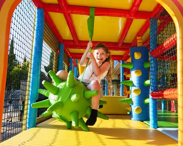 Child riding the hanging play obstacle inside the Circus-themed Playhouse on Wheels mobile playground.