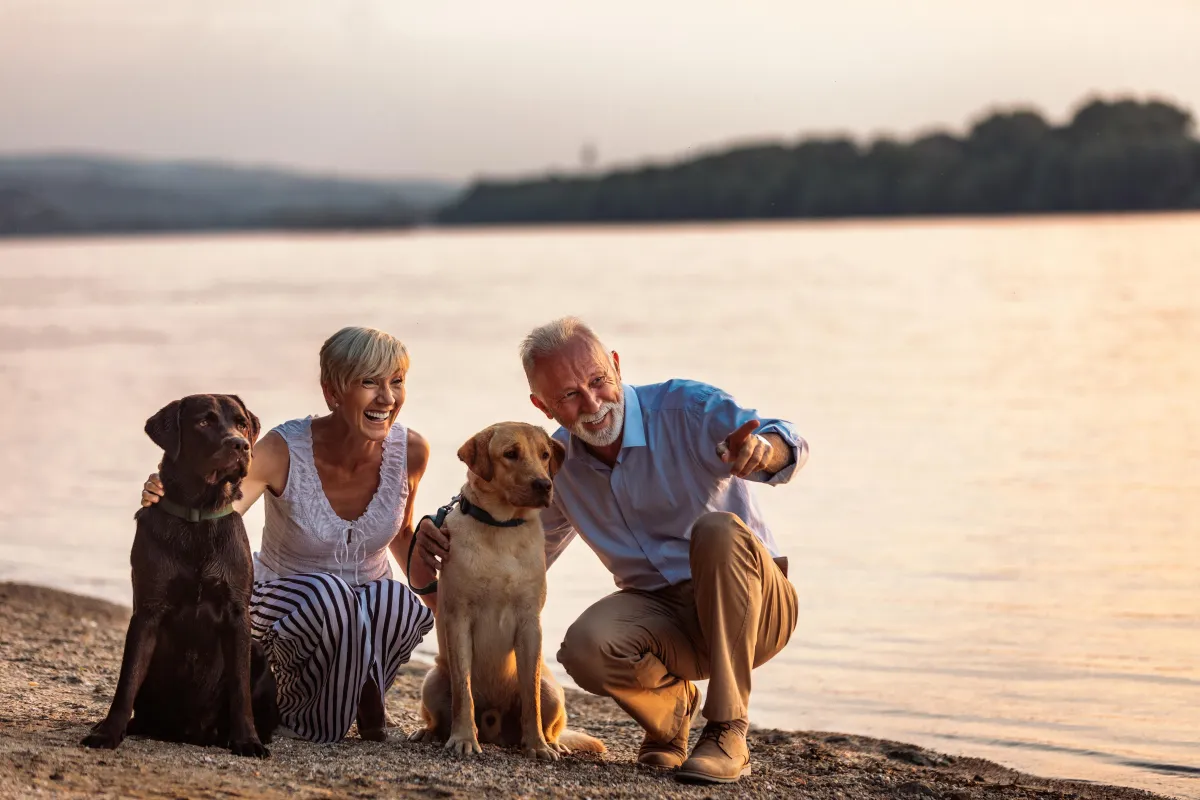 Happy retired senior couple on a lake with two dogs.