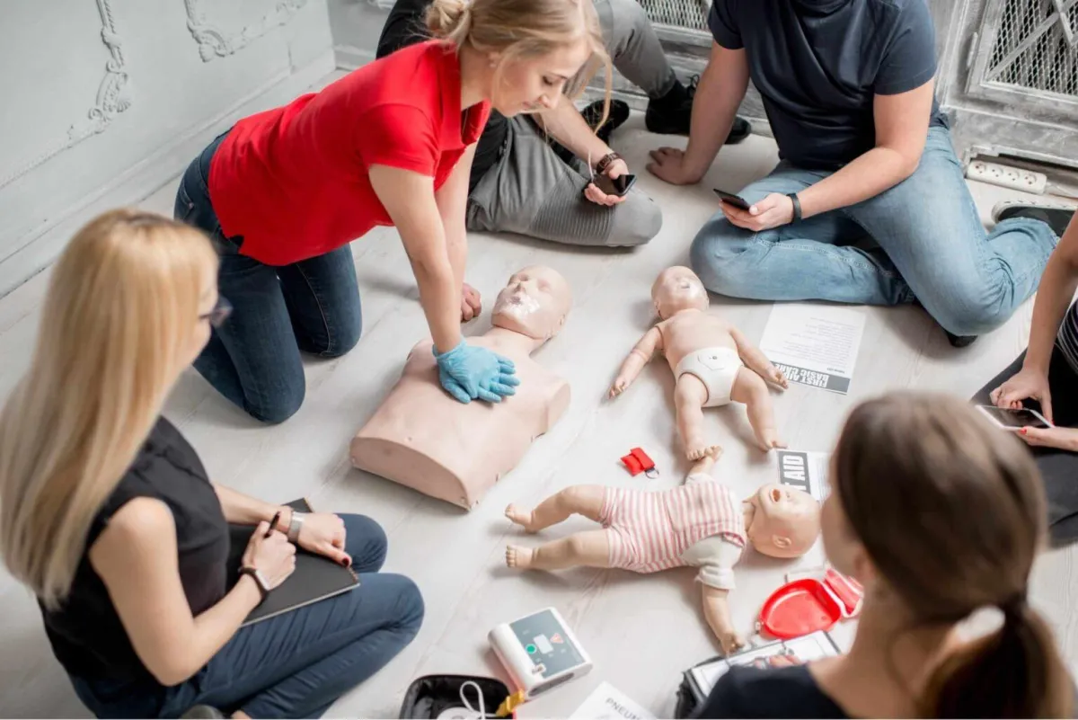 Group of people learning adult, child and infant compressions and CPR techniques.