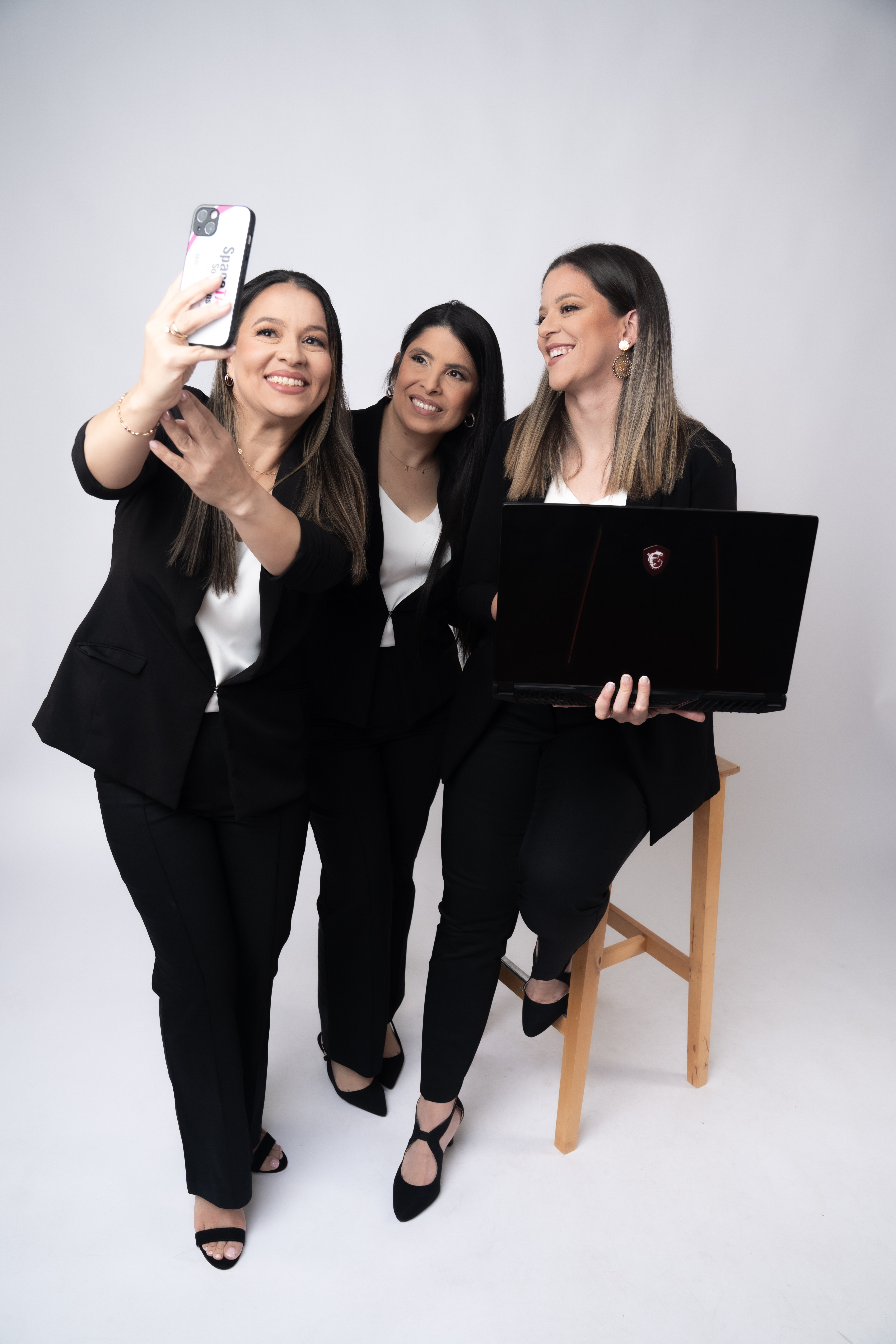 A group of young adults of various backgrounds gathered around a table, each using a smartphone to follow SpaceTax Solutions on social media. The setting is a cozy café with natural light, plants, and a friendly atmosphere.