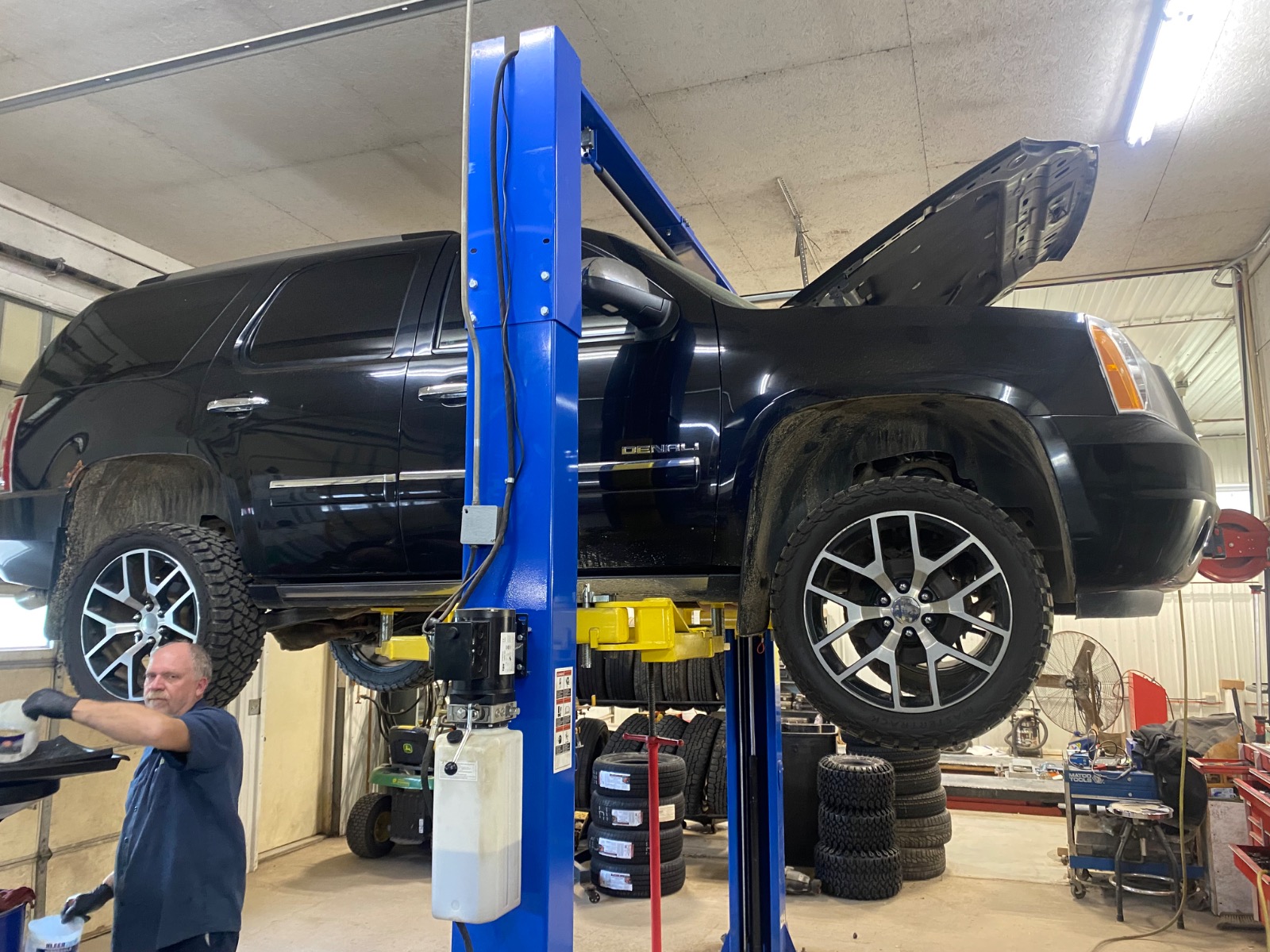 A mechanic servicing a black SUV on a hydraulic lift bay at Wilder's Tire & Auto Service in Hastings, MI