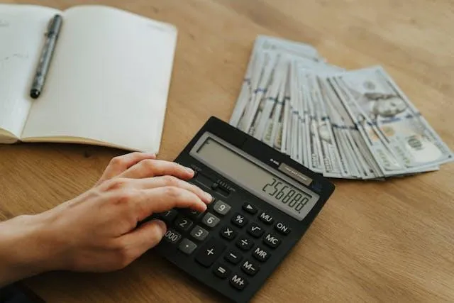 Person using calculator with US dollar bills and notebook, representing financial tax strategy planning