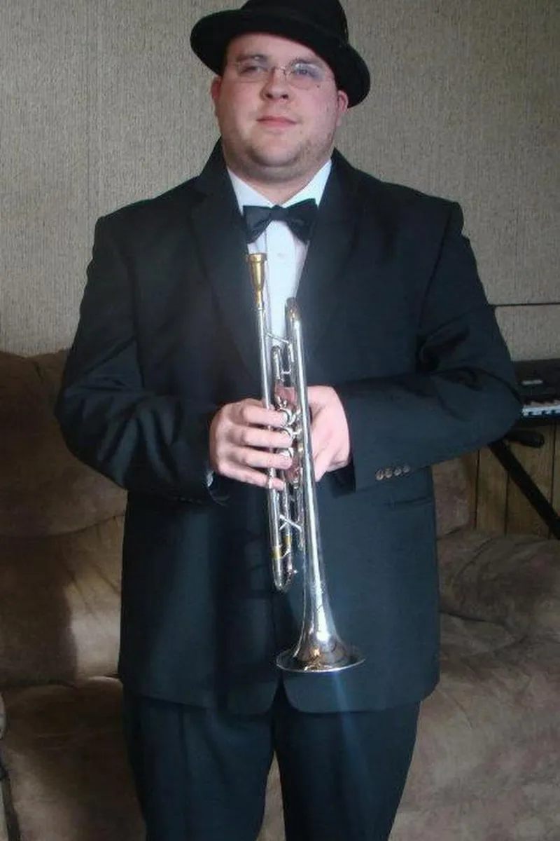 A music teacher, sits beside a grand piano holding a music sheet, focused and ready for the lesson. The room is bright and inviting, with natural light highlighting the elegant piano. Located in Farmington , Utah.