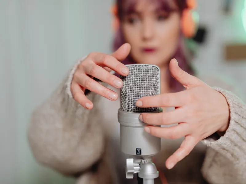An adult, dressed in a colorful long sleeve and eyeglasses, sits attentively at a sleek digital keyboard, their fingers moving gracefully over the keys. The soft glow of a tilt light bathes the scene, casting an inviting, warm ambiance around them.