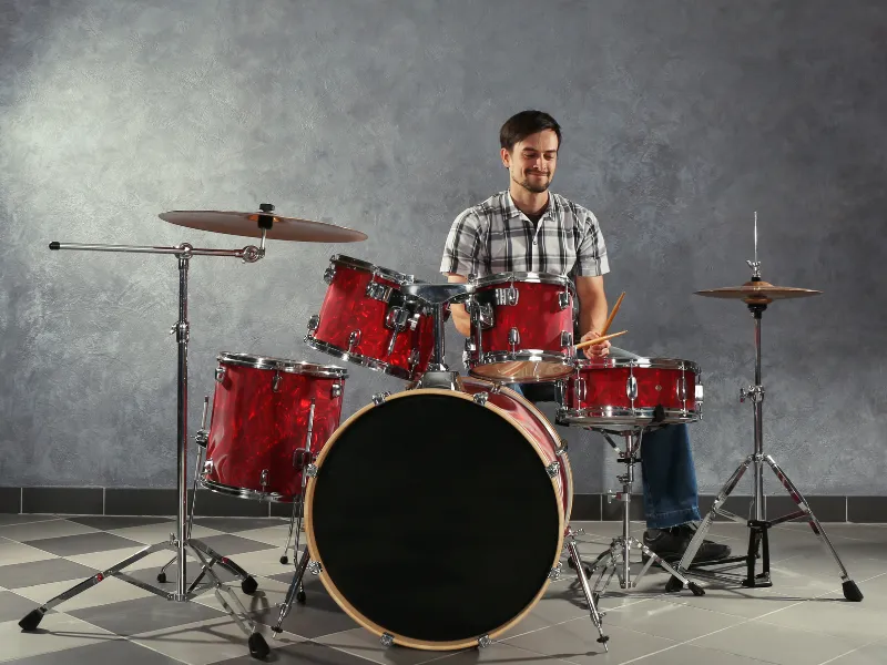 An adult, dressed in a colorful long sleeve and eyeglasses, sits attentively at a sleek digital keyboard, their fingers moving gracefully over the keys. The soft glow of a tilt light bathes the scene, casting an inviting, warm ambiance around them.