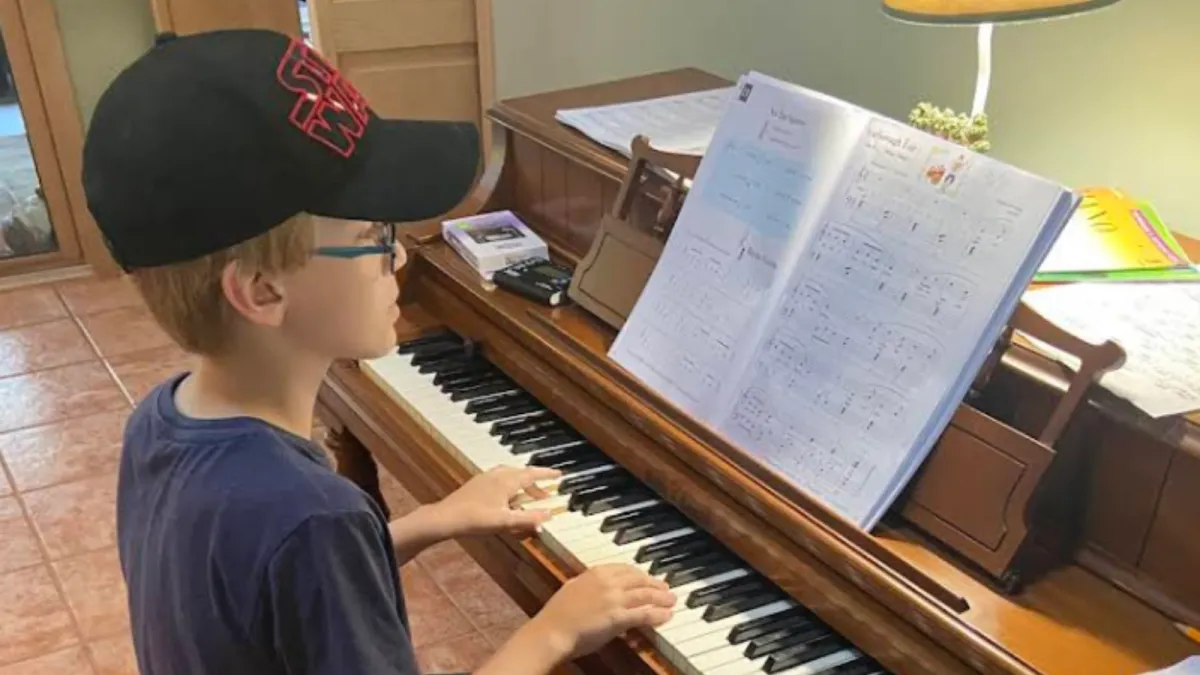Two children playing an upright piano together, one focusing on the lower keys and the other on the higher ones. Both kids are smiling, engaged in playing, in a cozy room with warm lighting. The scene highlights the joy of collaborative music-making.