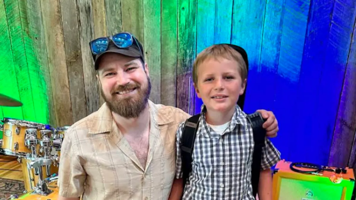 Two children playing an upright piano together, one focusing on the lower keys and the other on the higher ones. Both kids are smiling, engaged in playing, in a cozy room with warm lighting. The scene highlights the joy of collaborative music-making.