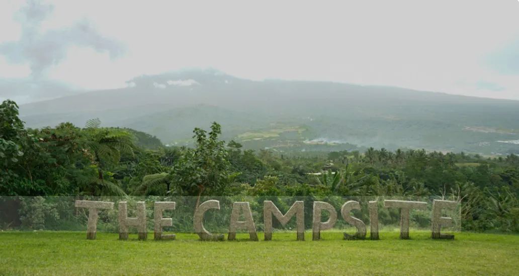 Tent with open flap facing sunrise over forest at The Campsite