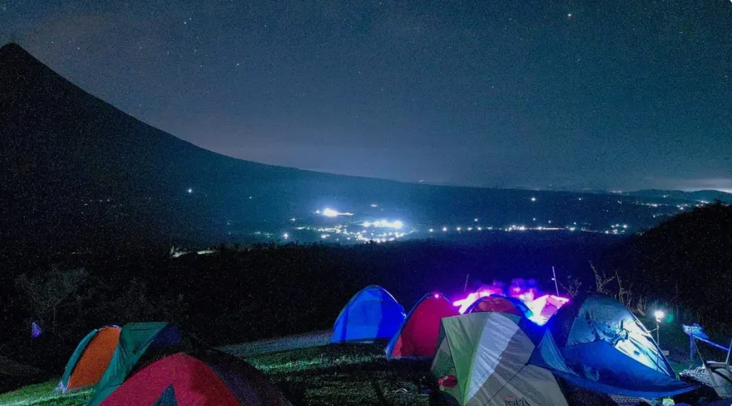 Campfire circle with people roasting marshmallows under string lights