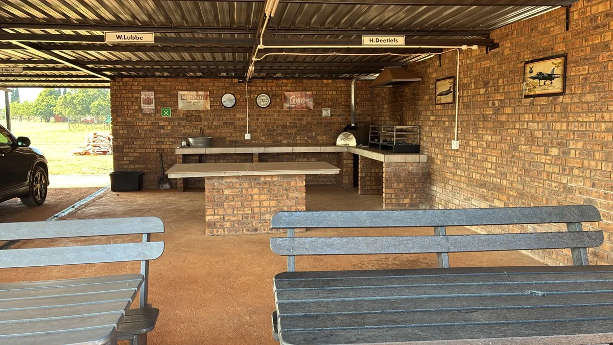 Scenic covered lapa with built-in braai facility and modern wooden tables