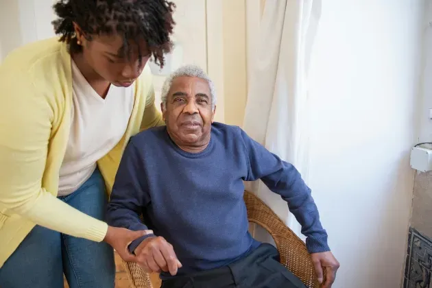 A female elder care professional helps an elderly gentleman sit down safely, providing the personal care needed, through Sumner In-home Care and Preferred Care at Home
