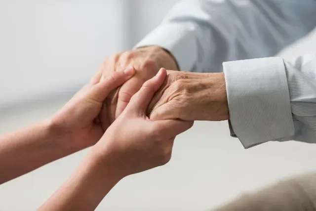 A young woman holds the hands of an elderly man with dementia while she provides at home dementia care, as provided by Sumner In-home Care and Preferred Care at Home