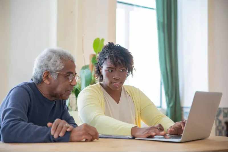 An elderly man getting help with his social media from his companion care caregiver, provided by Sumner In-home Care and Preferred Care at Home