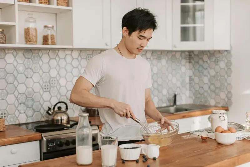 A male caregiver from Sumner In-home Care and Preferred Care at Home prepares a meal for an elderly client with special dietary needs as part of his personal care plan.