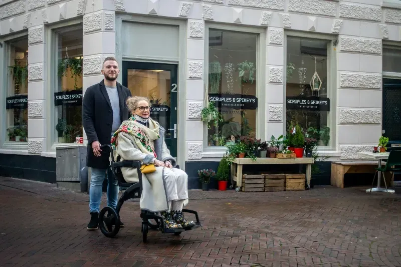 A male caregiver provided by Sumner In-home Care and Preferred Care at Home helps transport and elderly woman in a wheelchair as part of his personal care duties.
