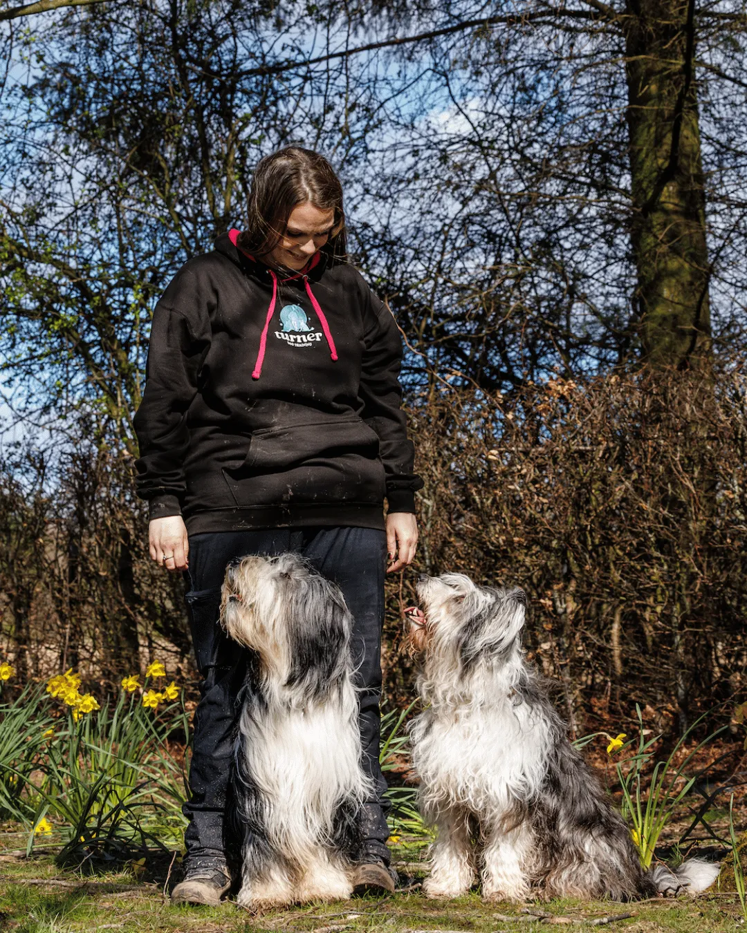 person in black jacket and gray pants holding black and brown short coated small dog