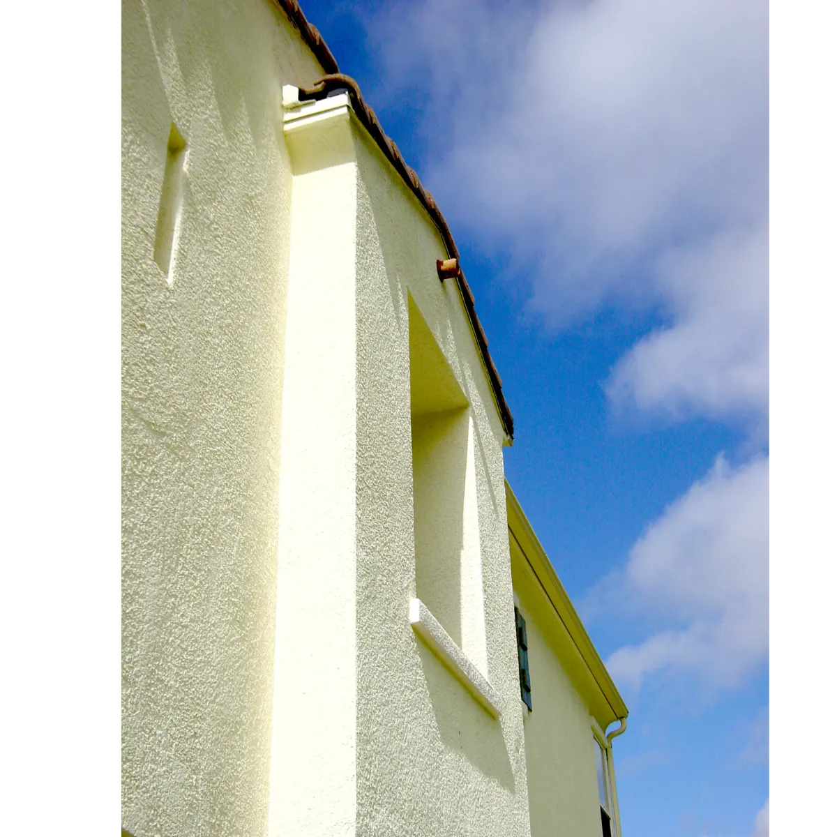 Tan Stucco on the side of a house with a blue sky