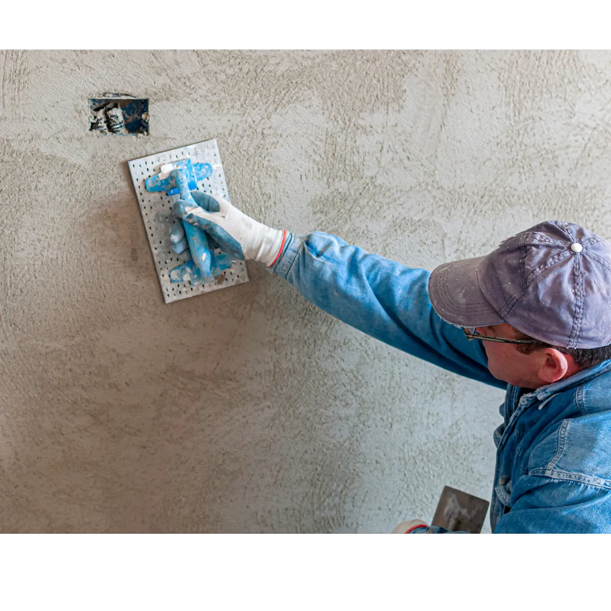 man with glasses and a hat applying stucco