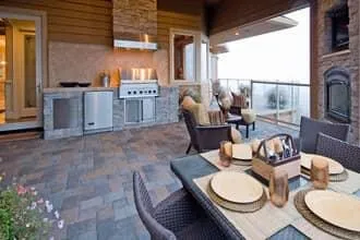 Outdoor masonry kitchen with grill and paver flooring