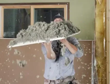 Contractor removing old blown-in attic insulation for improved energy efficiency and indoor air quality
