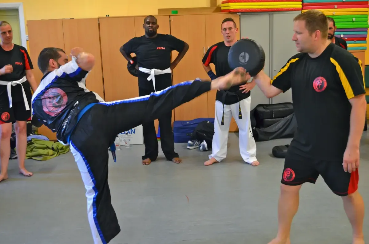 Chief Instructor Aaron Bannister explaining a kick with a student demonstrating