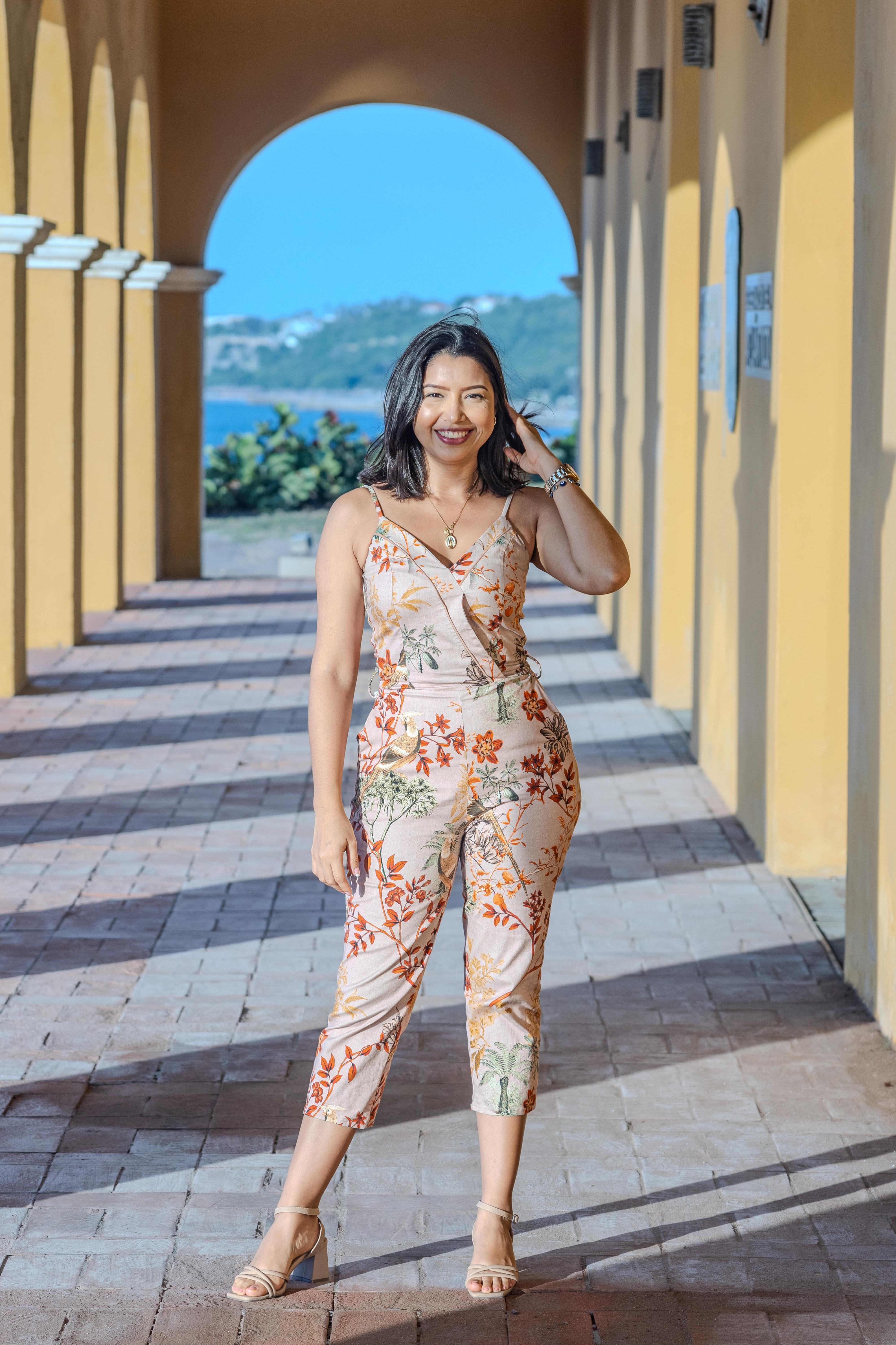 Woman posing in a bright yellow archway corridor with a scenic landscape behind her