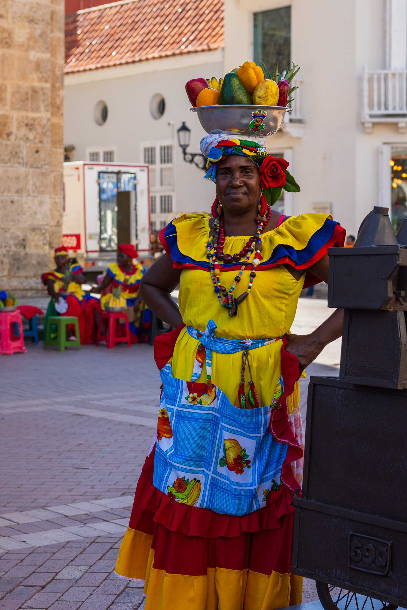 Afro-Colombian woman dressed in traditional colorful attire holding a fruit basket in Cartagena
