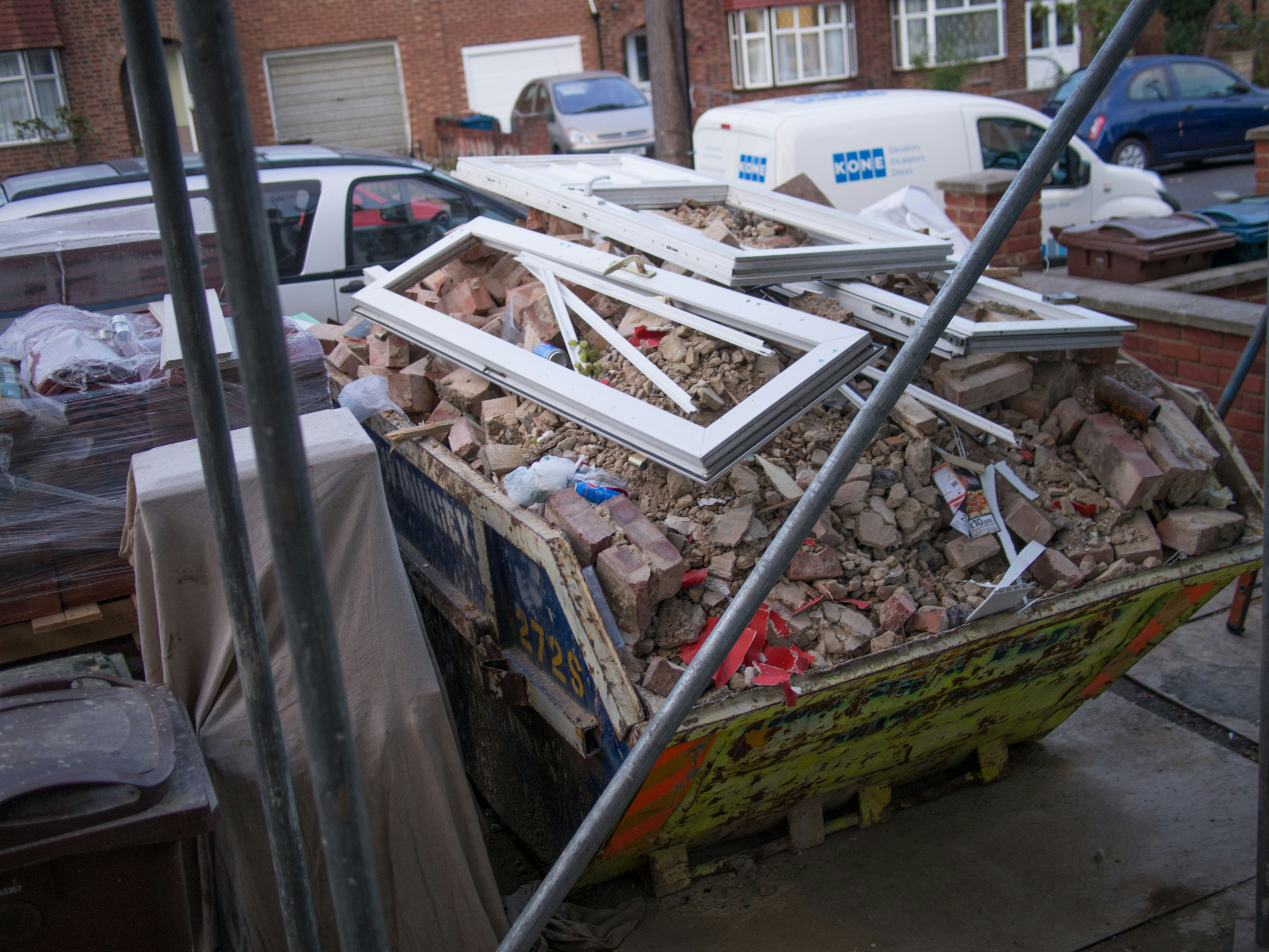 skip bin with a load of construction demolition waste like bricks and door frames