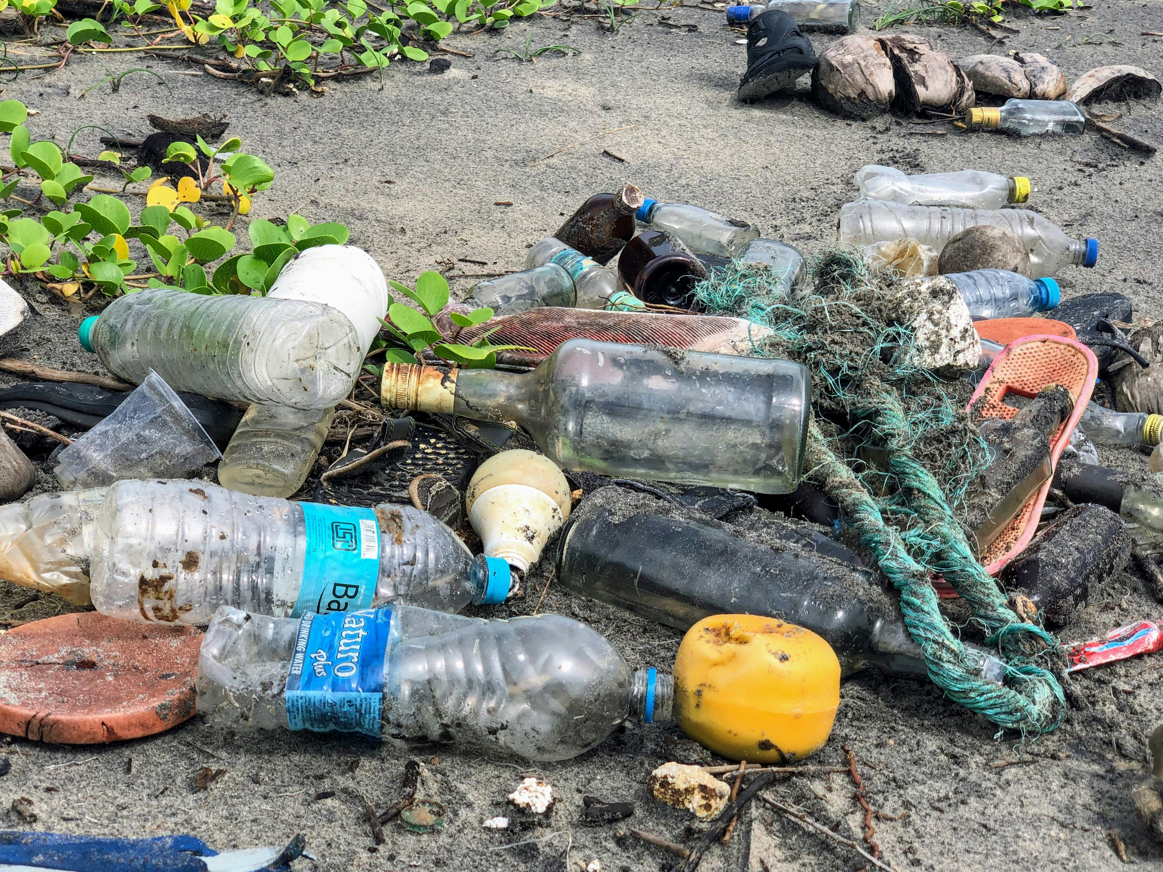 plastic bottles, glass bottles, dumped outside on gravel