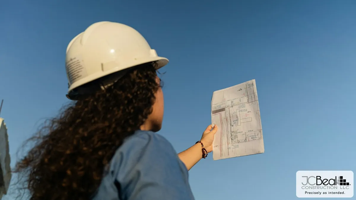 Construction professional reviewing building plans outdoors, JC Beal Construction branding