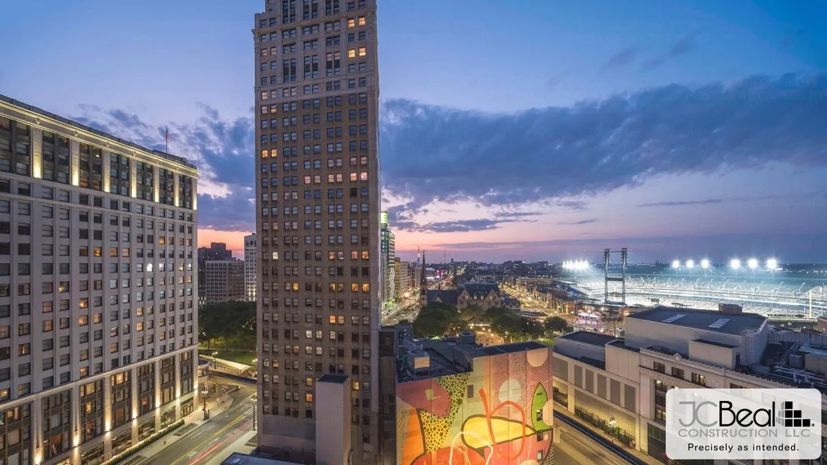 Historic Detroit high-rise tower at twilight above a revitalized downtown block