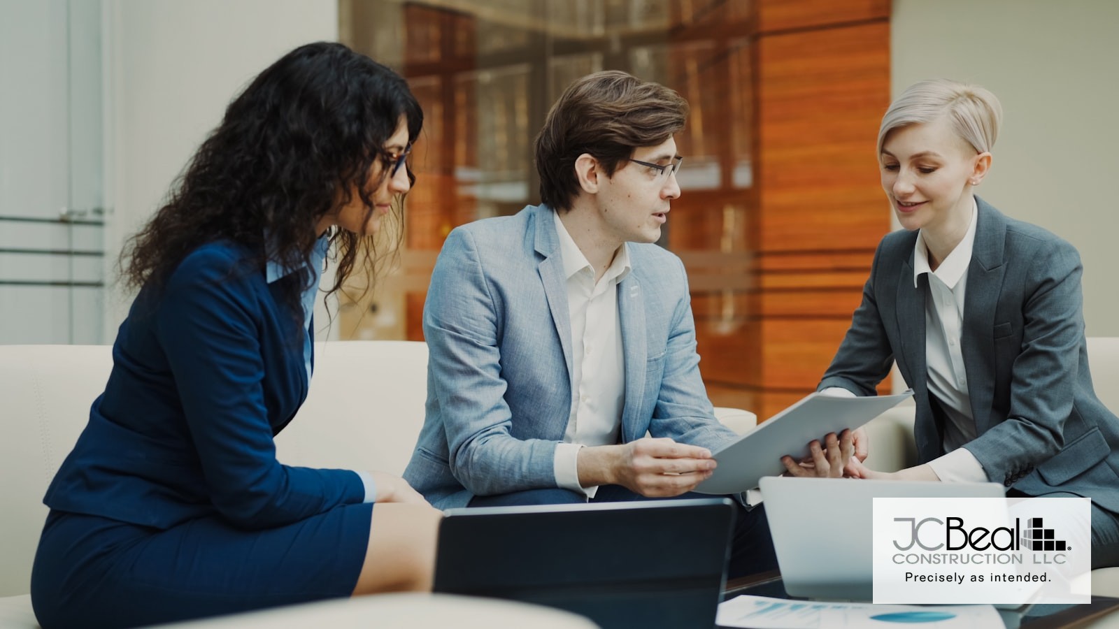 Three professionals reviewing a bid document together at a conference table