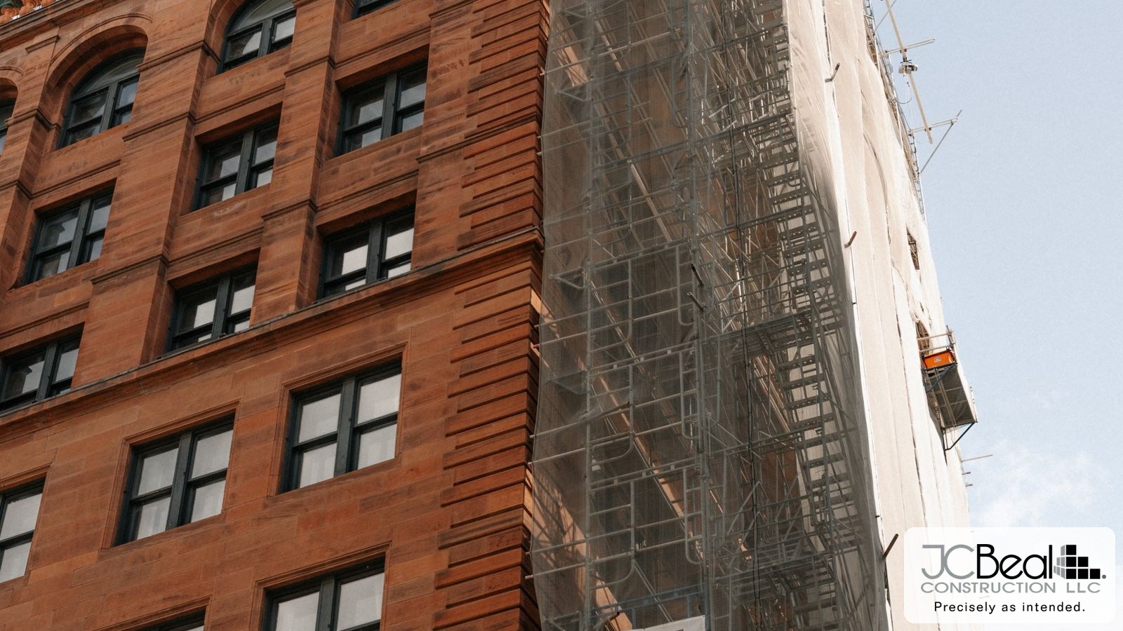 Historic red brick building under renovation with scaffolding on the facade