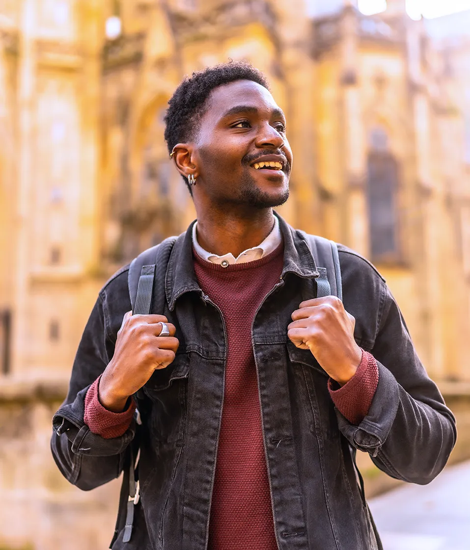 Graduate student with a backpack and a smile representing The Whigham School's seven core values while developing cultural intelligence, ethical leadership, and global perspective through immersive international education experience