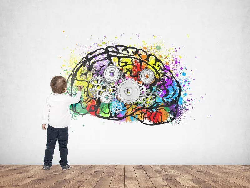 child pointing at a brain image with cogs on it.