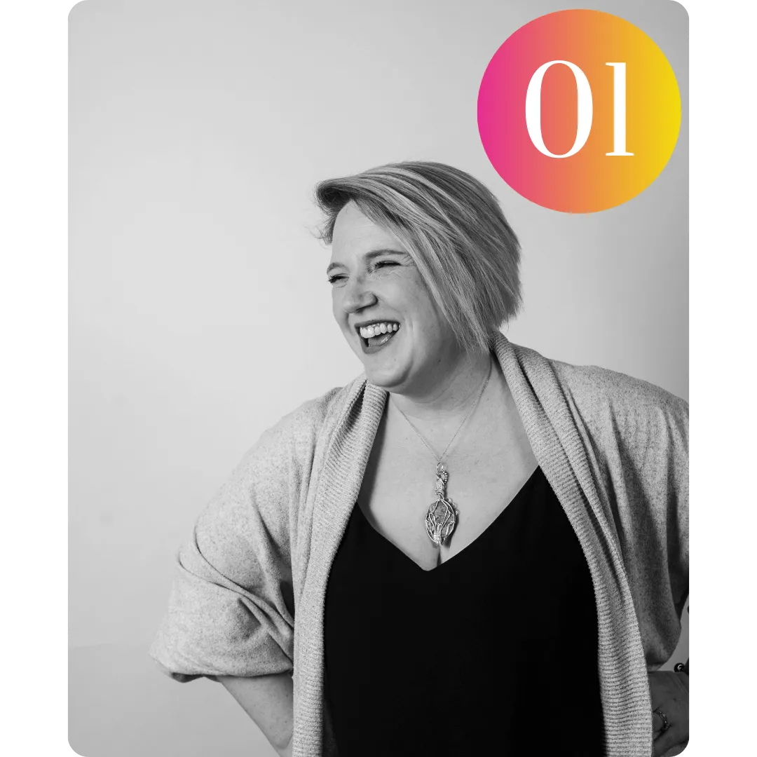 A black and white image of Lisa - a white woman with short hair smiling wearing a cardigan, black top and a necklace