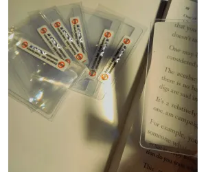 Image of branded pocket magnifying glasses with one over a book