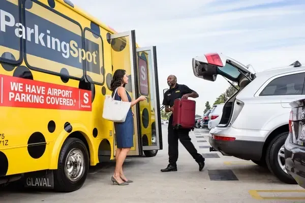 Person boarding a bus at the airport, carrying luggage.
