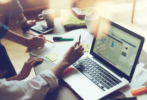 Collaborative workspace with laptop, sticky notes, and coffee cups, illustrating digital outreach planning for churches.